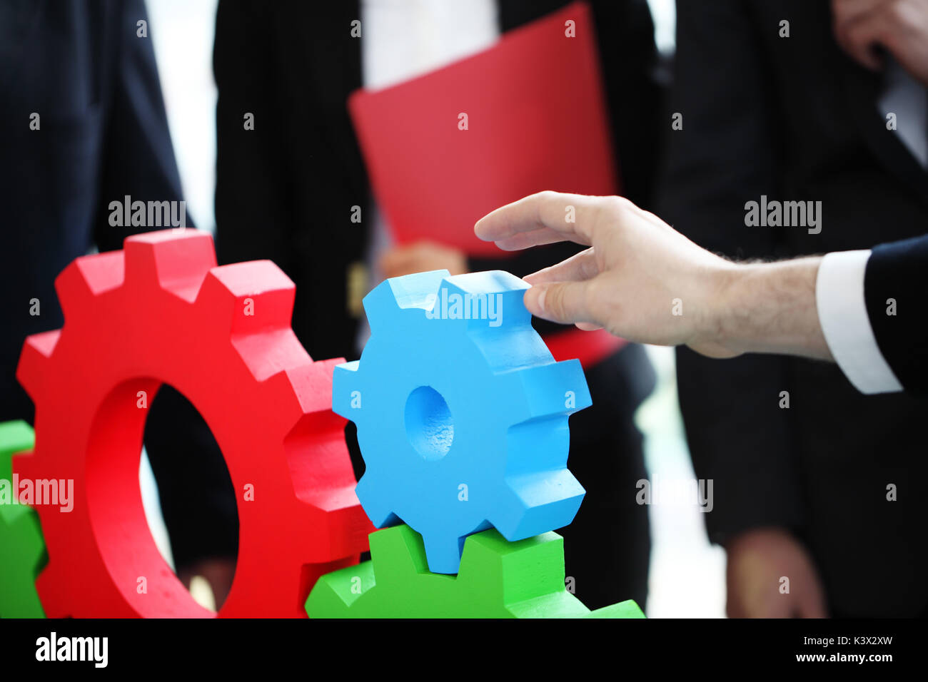 Business people assembling cogwheels, teamwork concept Stock Photo