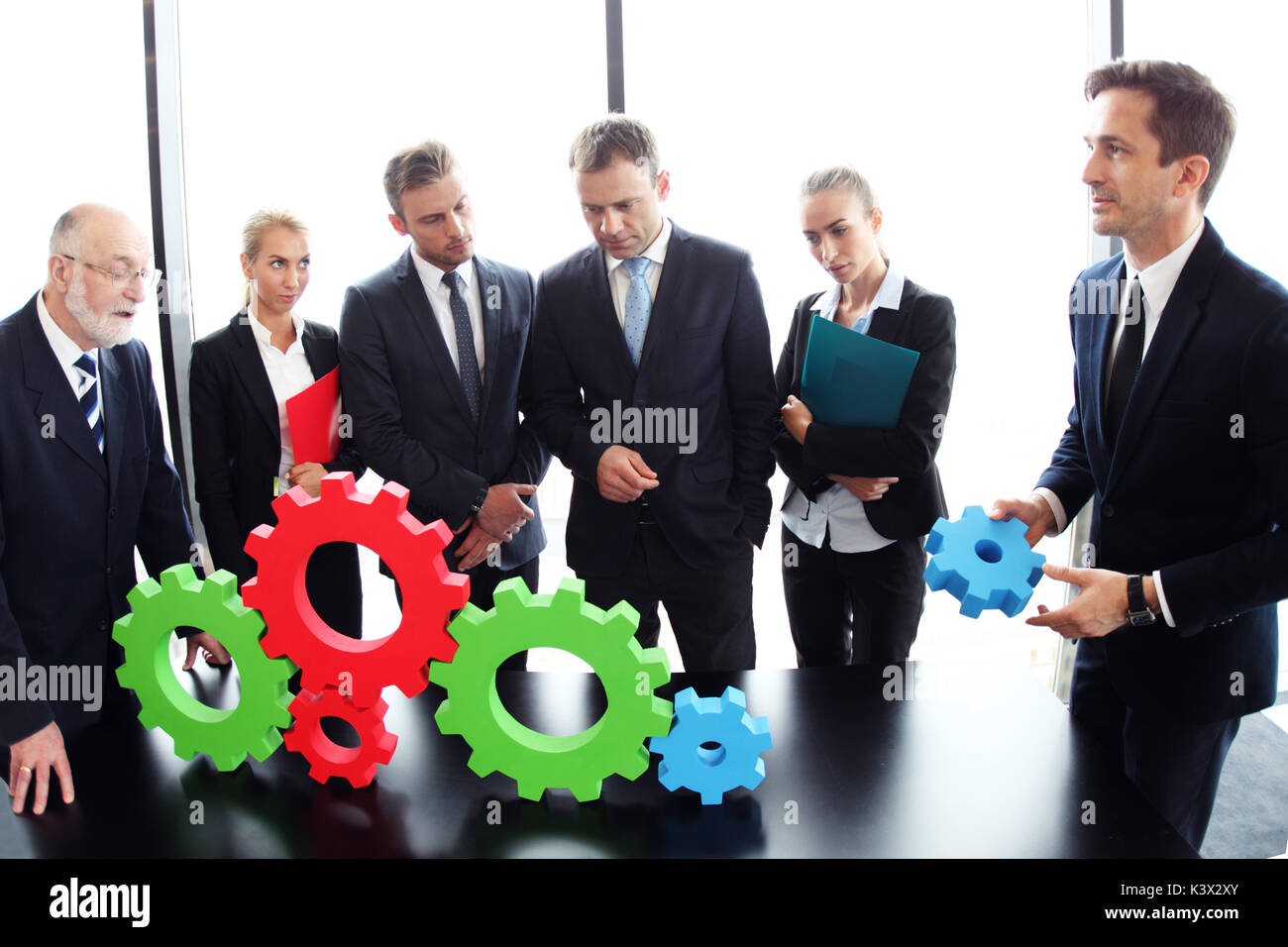 Business people assembling cogwheels, teamwork concept Stock Photo