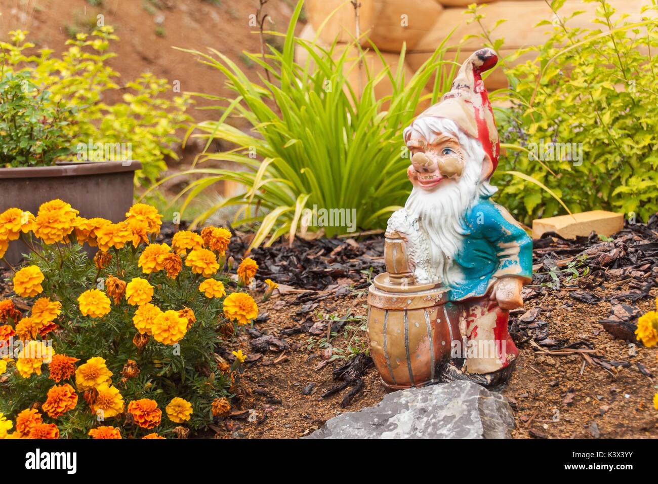 An old broken dwarf in the garden. Decoration in flowerbed Stock Photo