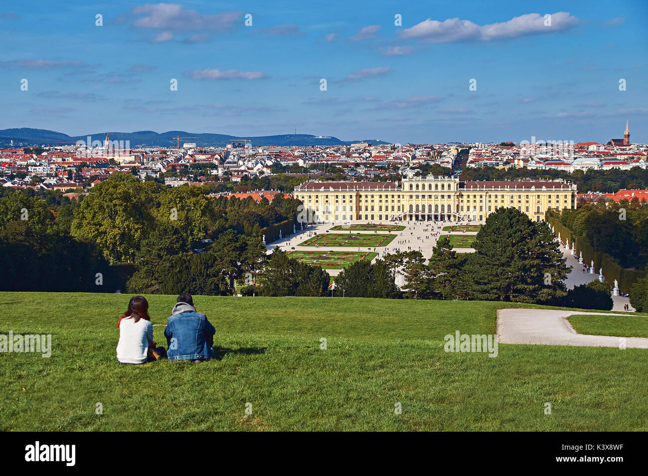 Vienna, Austria - September 24, 2014: Couple of tourists sitting on the grass with the view of Schonbrunn palace Stock Photo