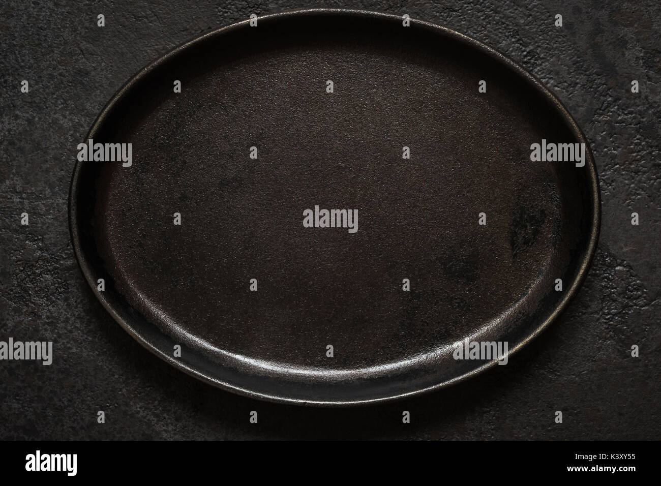 Empty rustic black cast iron plate On Dark concrete background. Top view with copy space. Stock Photo
