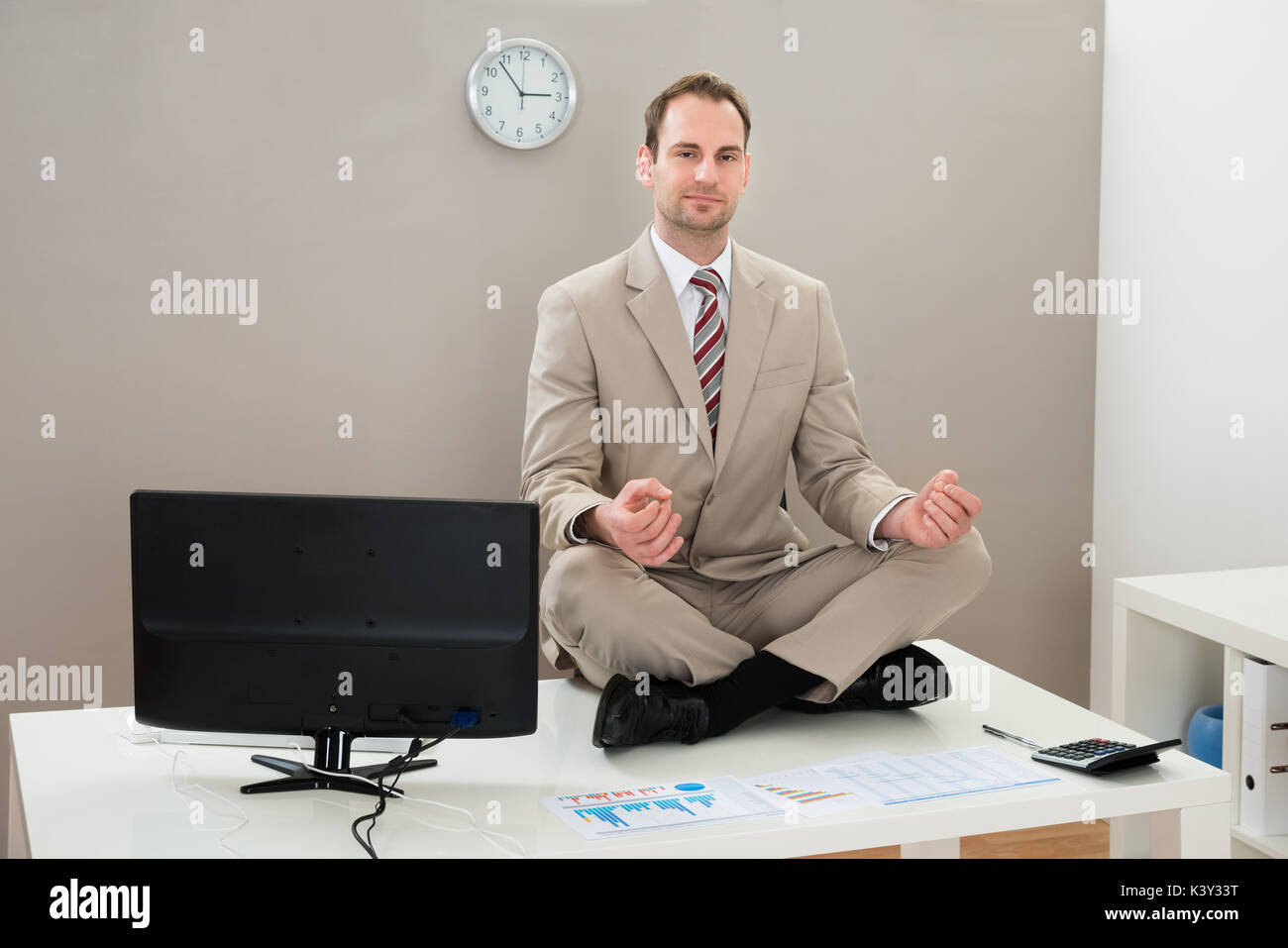 Businessman Doing Yoga On Desk In Office Stock Photo - Alamy