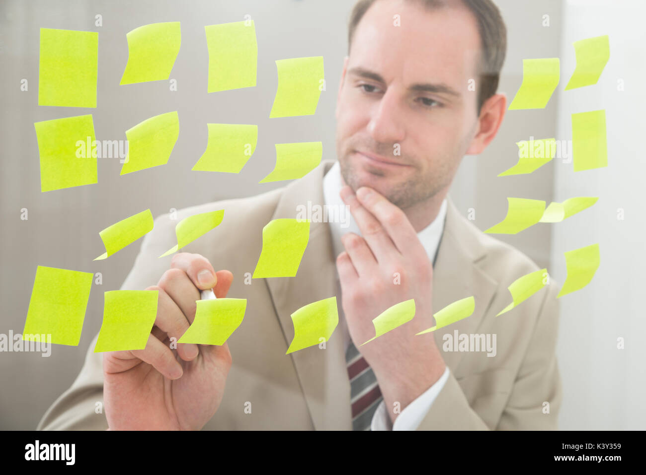 Contemplating Businessman Making Notes On Adhesive Paper Stock Photo