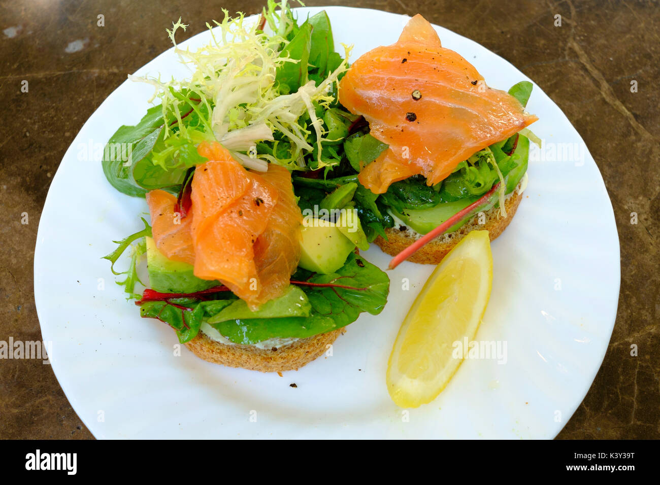 Smoked Salmon and Avocado open sandwich with cream cheese on granary Bread with salad garnish Stock Photo