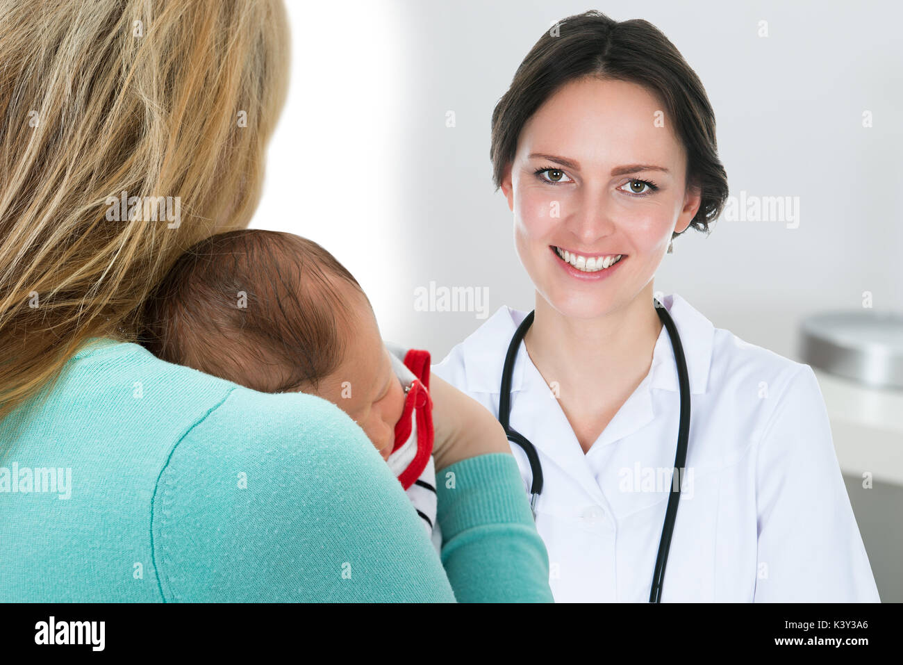 Close-up Mother Carrying Baby And Happy Female Doctor Stock Photo