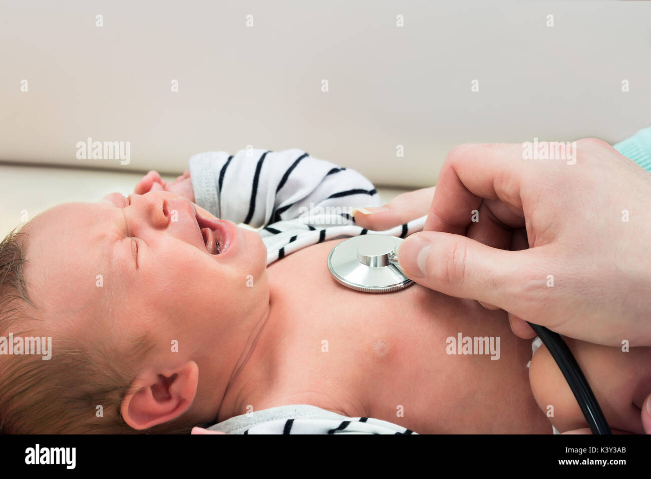 Little Newborn Baby Crying While Examined By Doctor Stock Photo