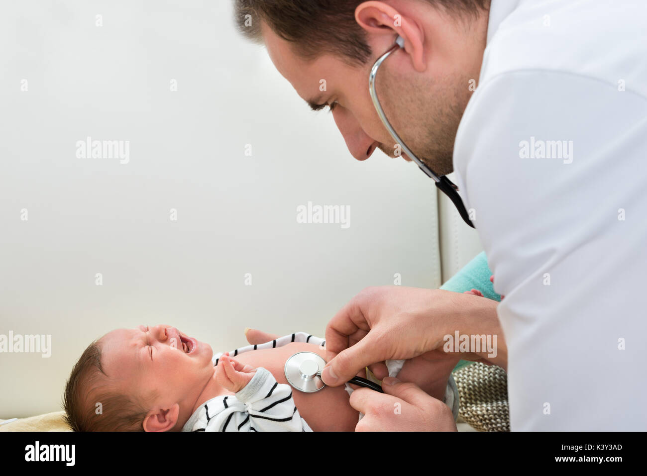 Close-up Of Male Doctor Examining Crying Baby Stock Photo