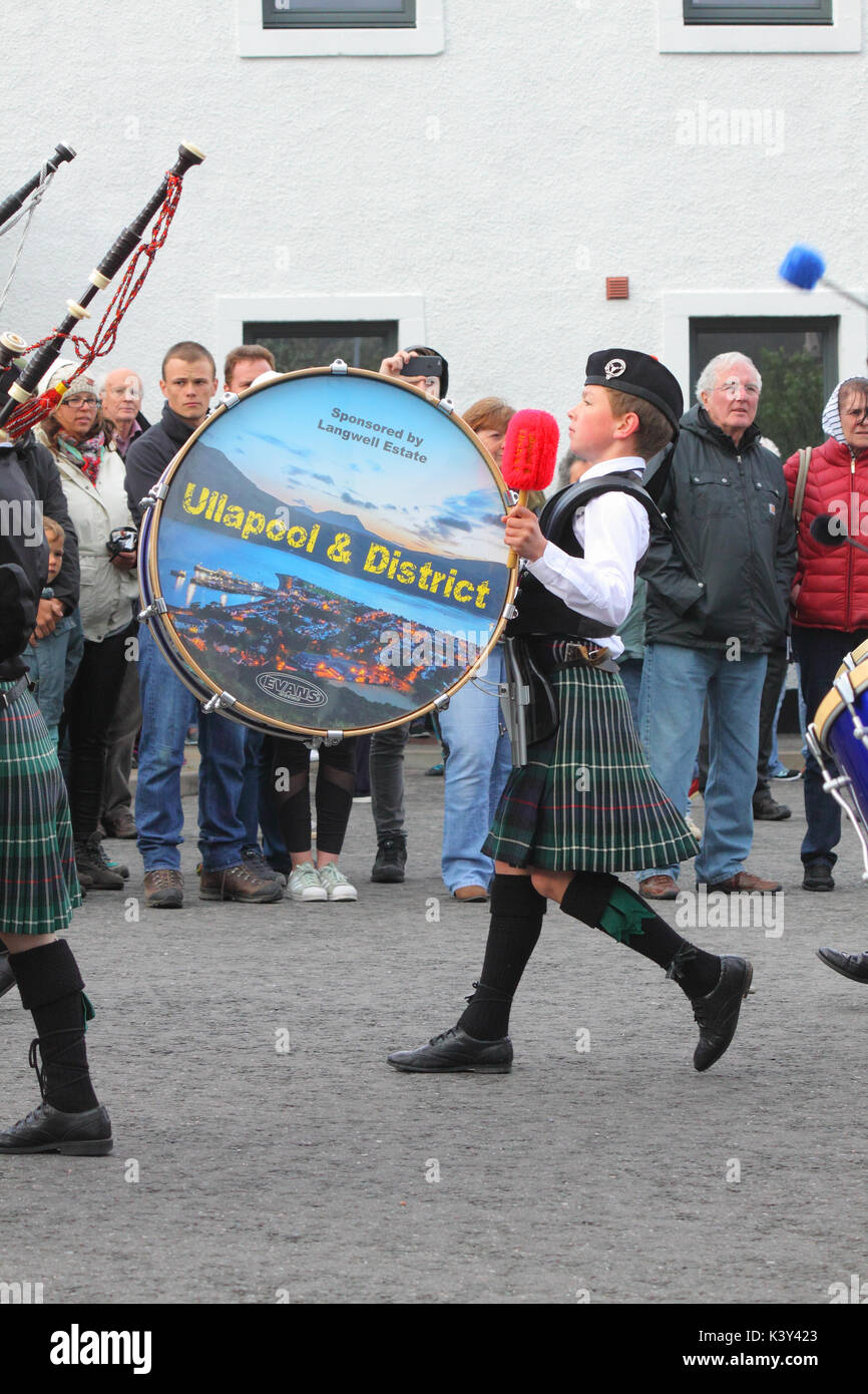 Young lad playing the bass drum for Ullapool & District Junior Pipe Band playing in Ullapool, Scotland Stock Photo