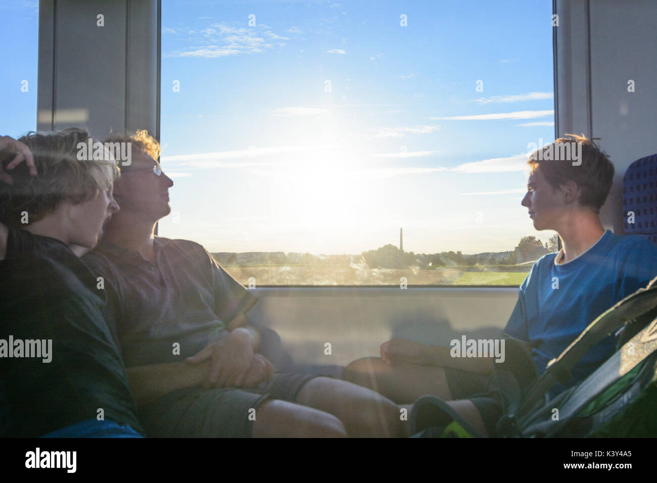 father man, 2 boys sitting in train, sun, relaxed, Augsburg, Schwaben, Swabia, Bayern, Bavaria, Germany Stock Photo