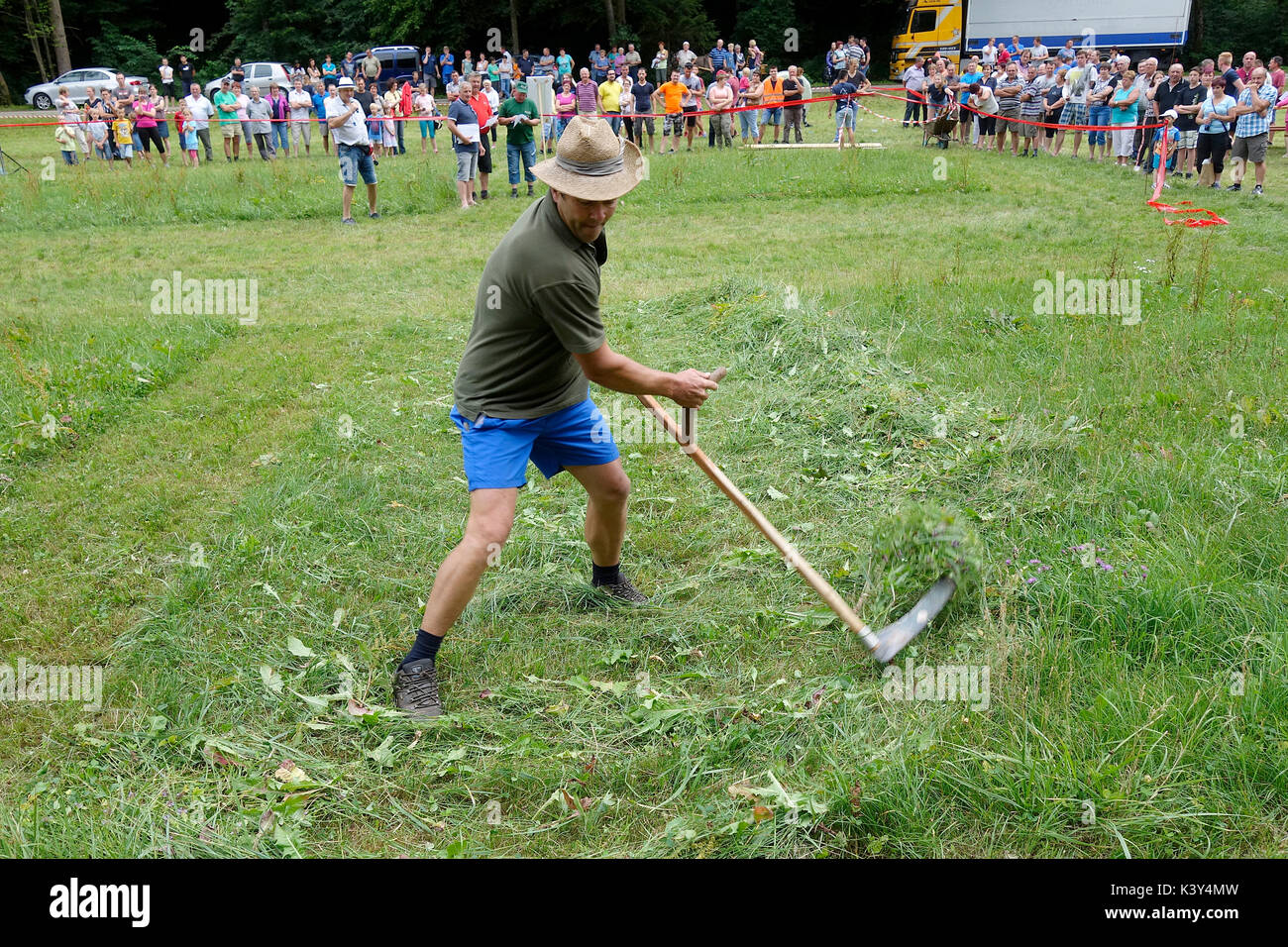 A men displays the skill of scythe grass moving. Farmer's games at village fair in Tržišče. Dolenjska, Slovenia Stock Photo