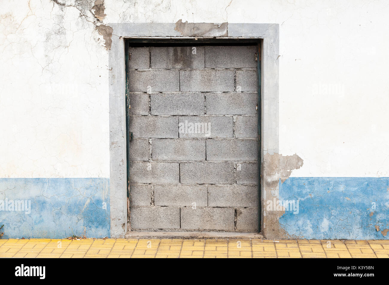 Doorway in old white wall blocked with concrete bricks Stock Photo
