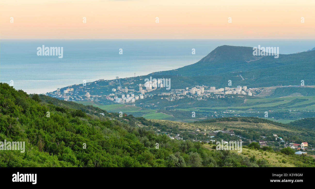 Coastal resort town between the mountains and hills near the sea at dawn. The Peninsula of Crimea, Alushta Stock Photo