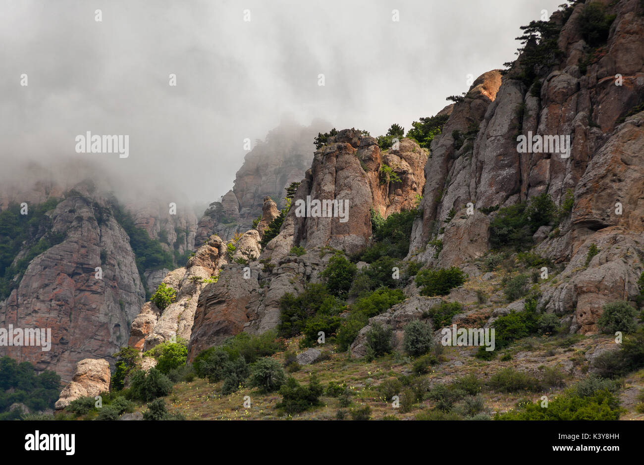 Clouds passing below the top of the mountain. Rocks of unusual shape. The strange cluster of rocks formed under the influence of wind and rain, at daw Stock Photo