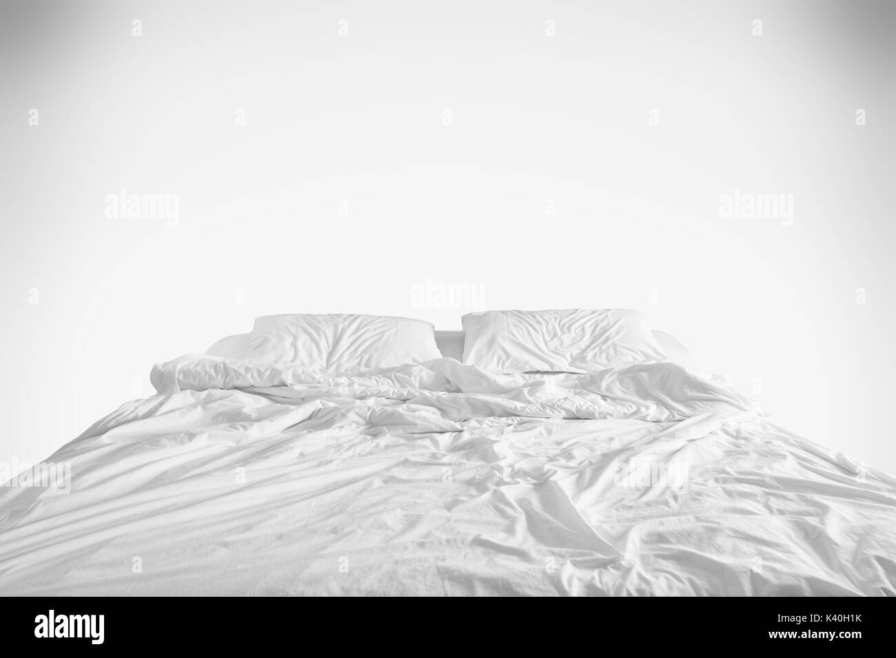 unmade bed with crumpled bed sheet, a blanket and pillows after comfort duvet sleep waking up in the morning on white background Stock Photo
