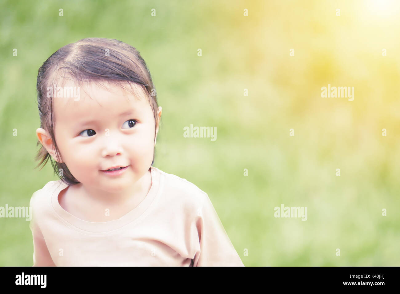 portrait of little girl playing in the green garden with warm tone and soft focus ,asian baby Stock Photo
