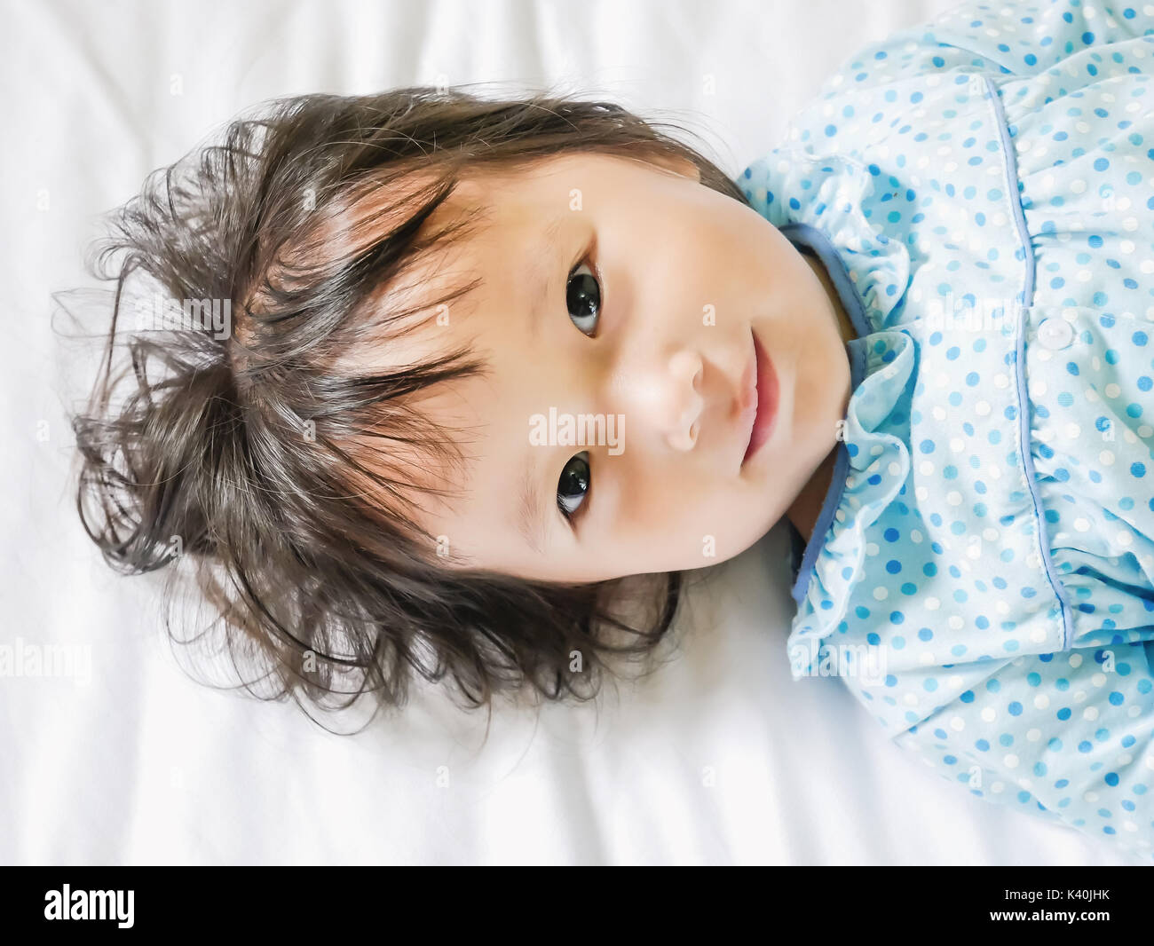 child lying smile in white bedding room for copy space :soft focused Stock Photo
