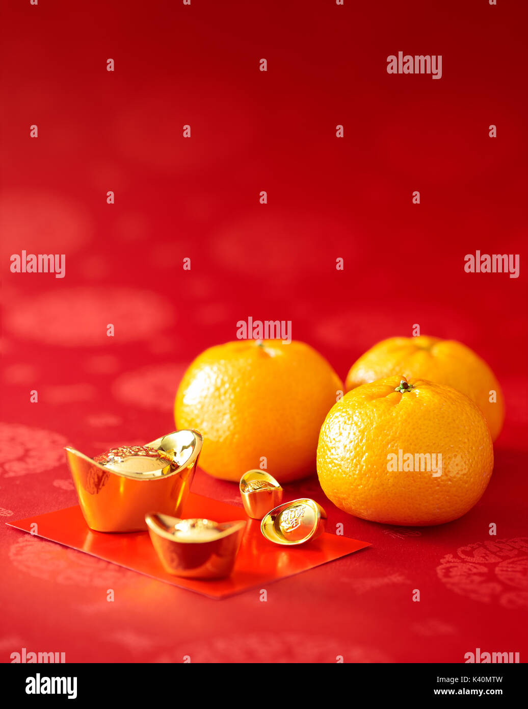 Chinese New Year - Mandarin orange, gold sycee (Foreign text means wealth) and red packet Stock Photo