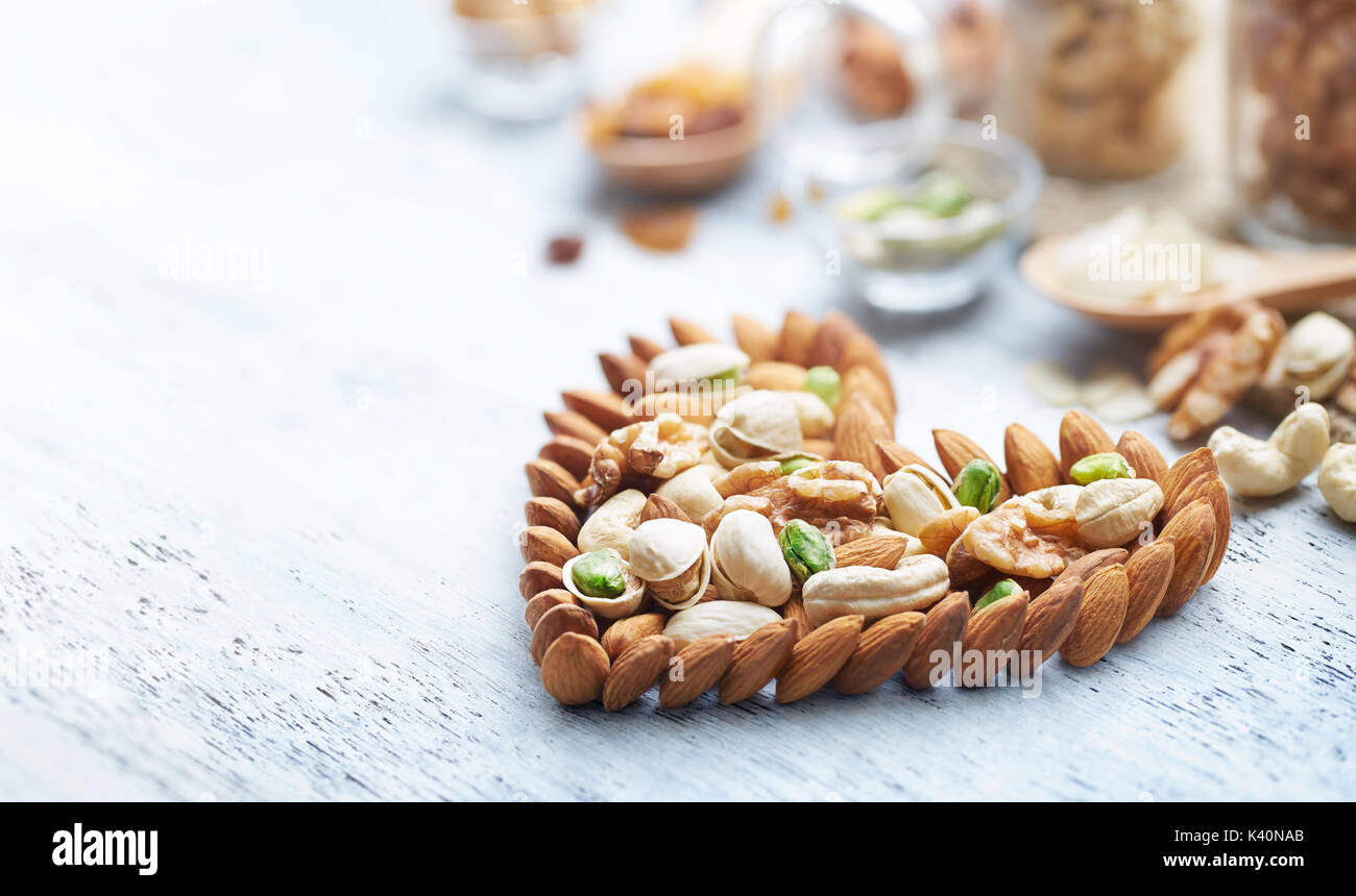 Mixed nuts forming a heart-shape on white painted wood background Stock Photo