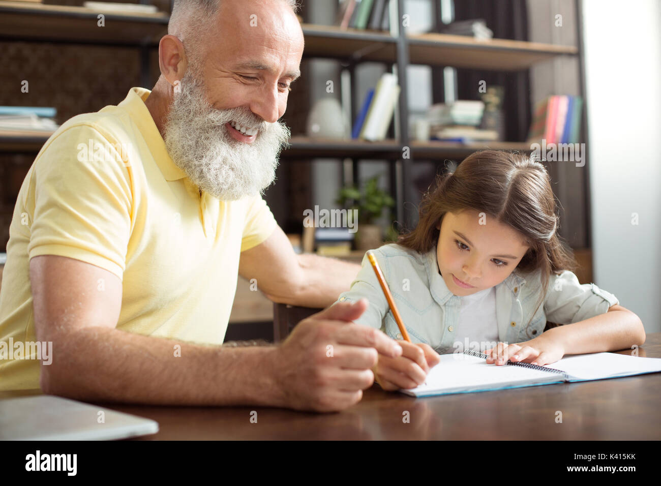 Smiling grandfather helping his granddaughter with homework Stock Photo