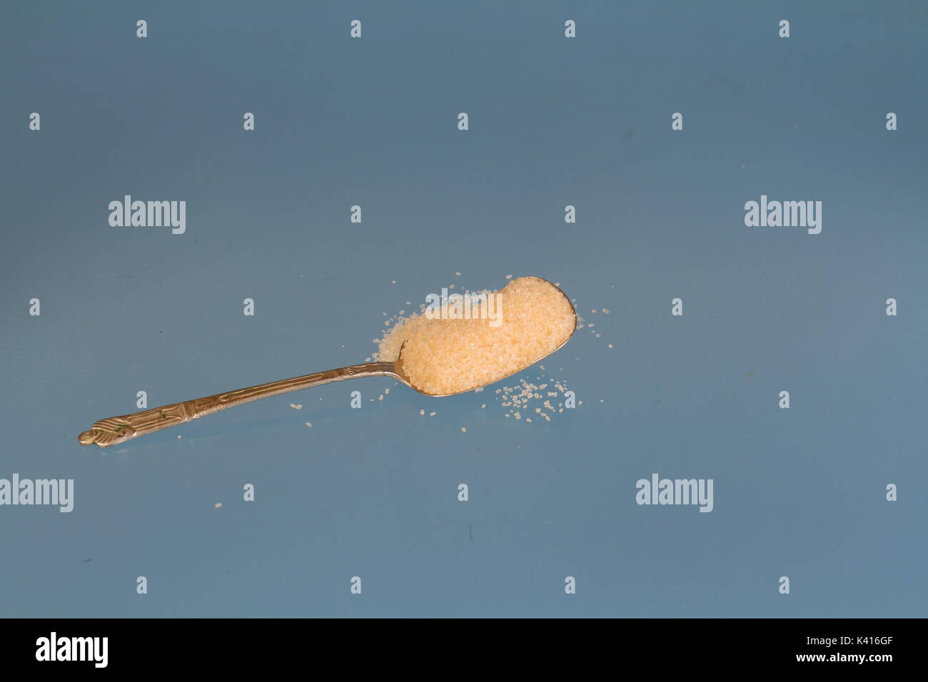 A teaspoon heaped with golden sugar against a clear background in landscape format with copy space Stock Photo