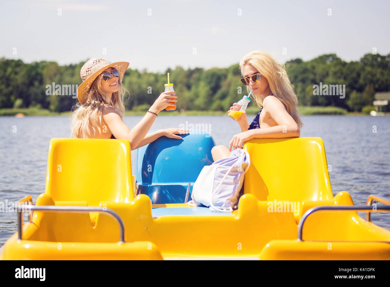 A photo of two beautiful friends relaxing on paddle boat and drinking