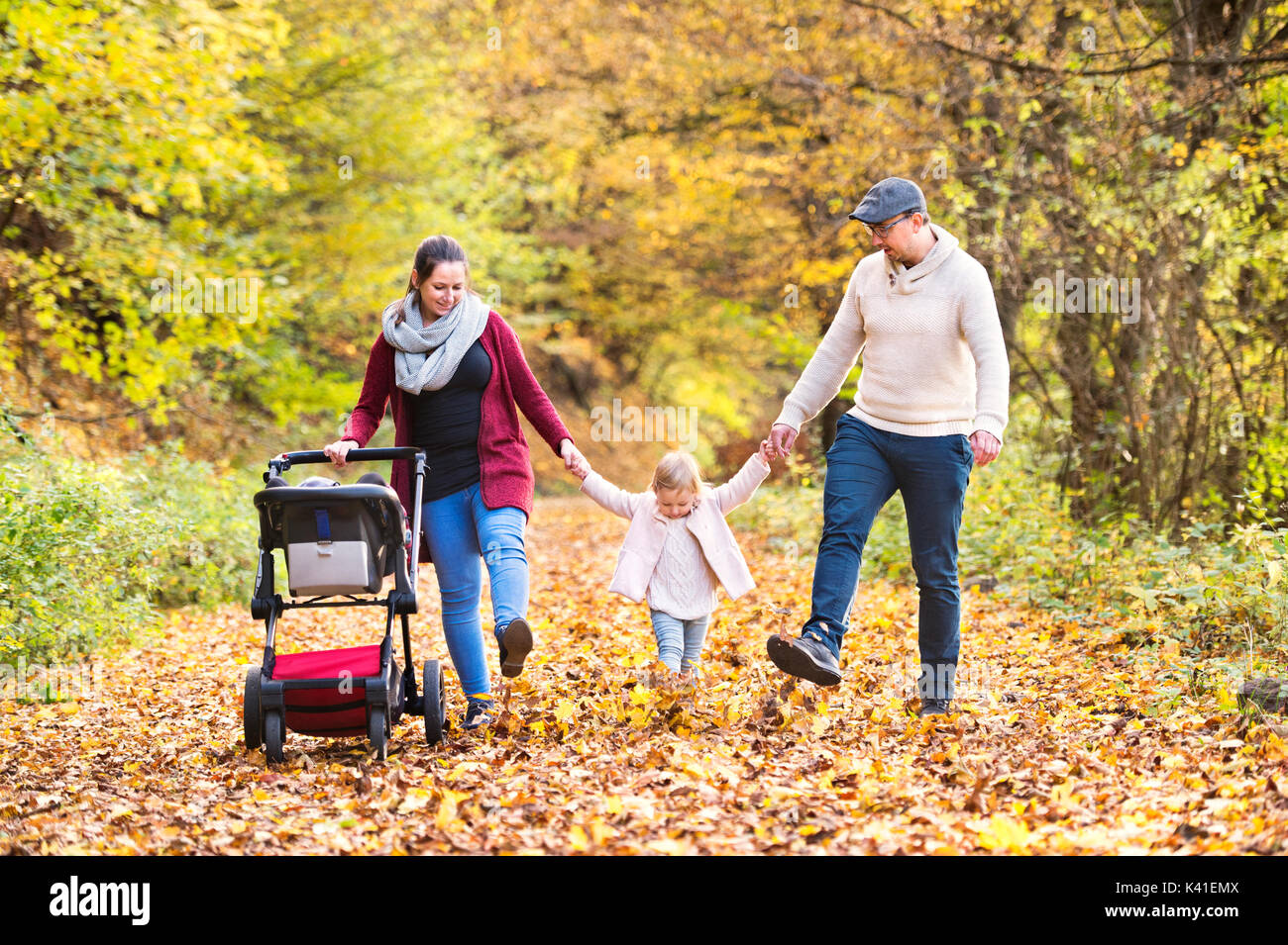 Beautiful young family on a walk in autumn forest Stock Photo - Alamy