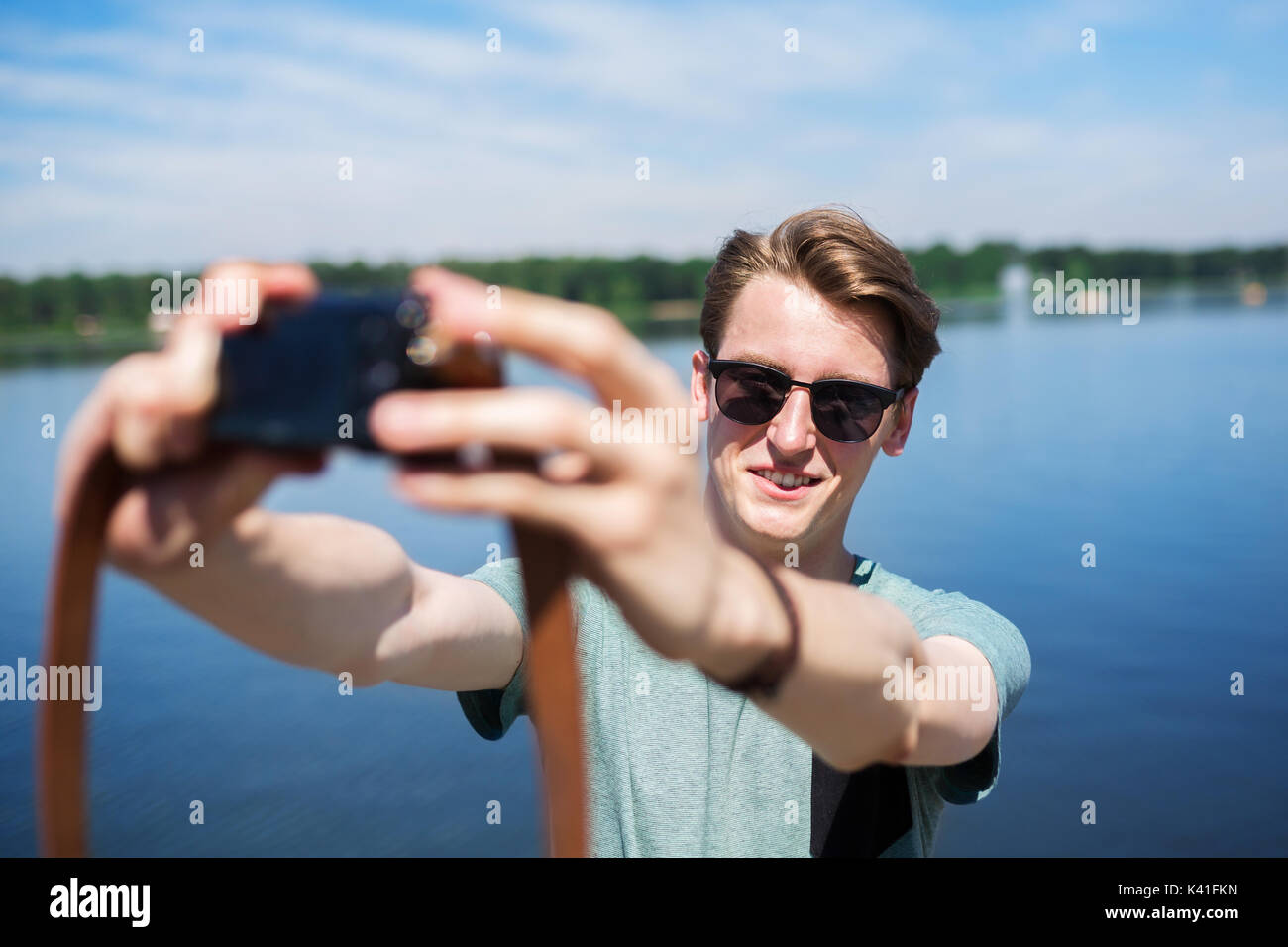 A photo of young, cheerful man taking himself a photo at the lake. Stock Photo