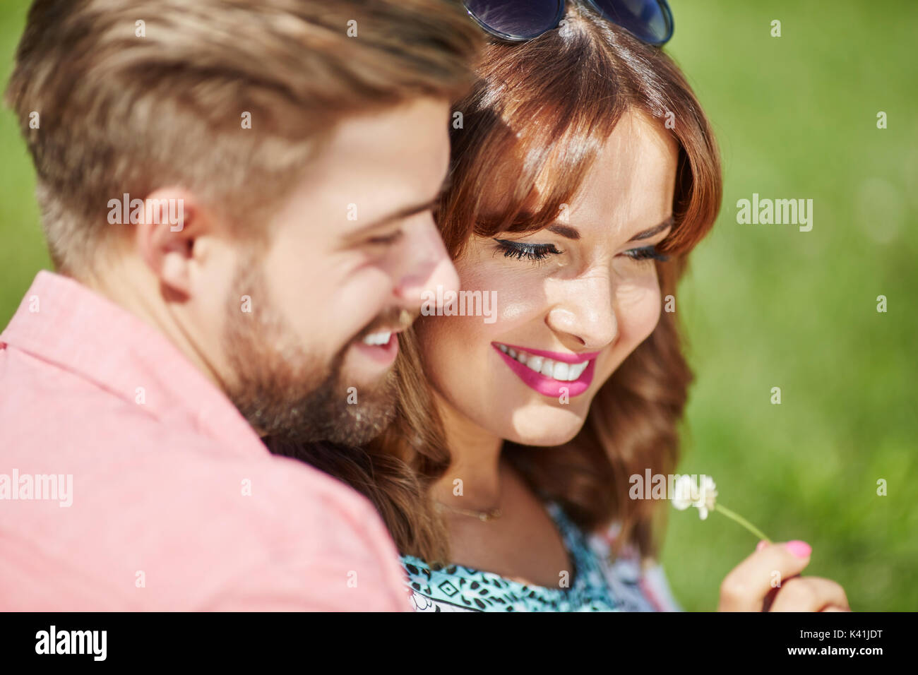 A photo of young, happy couple head over heels in love. The man is giving his girlfriend a flower. Stock Photo