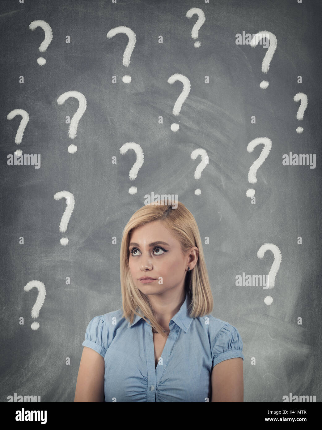 Thinking business woman looking up on many questions mark isolated on gray wall background Stock Photo