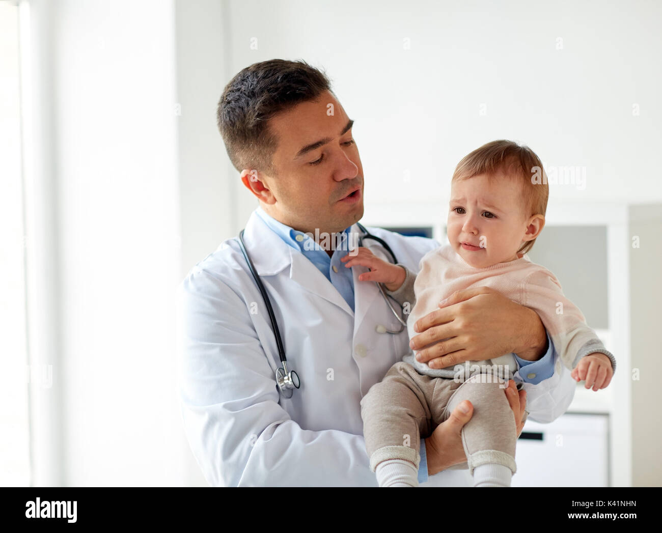 doctor holding crying baby at clinic Stock Photo
