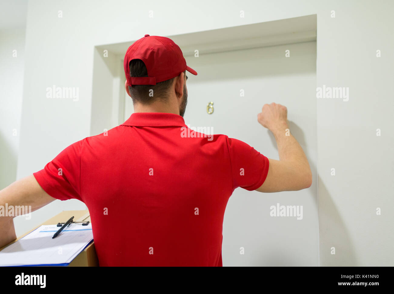 delivery man with parcel box knocking door Stock Photo