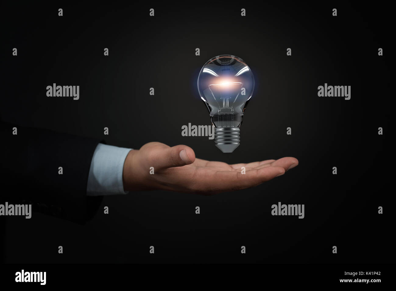 Hands of business person holding illuminated light bulb sign Stock