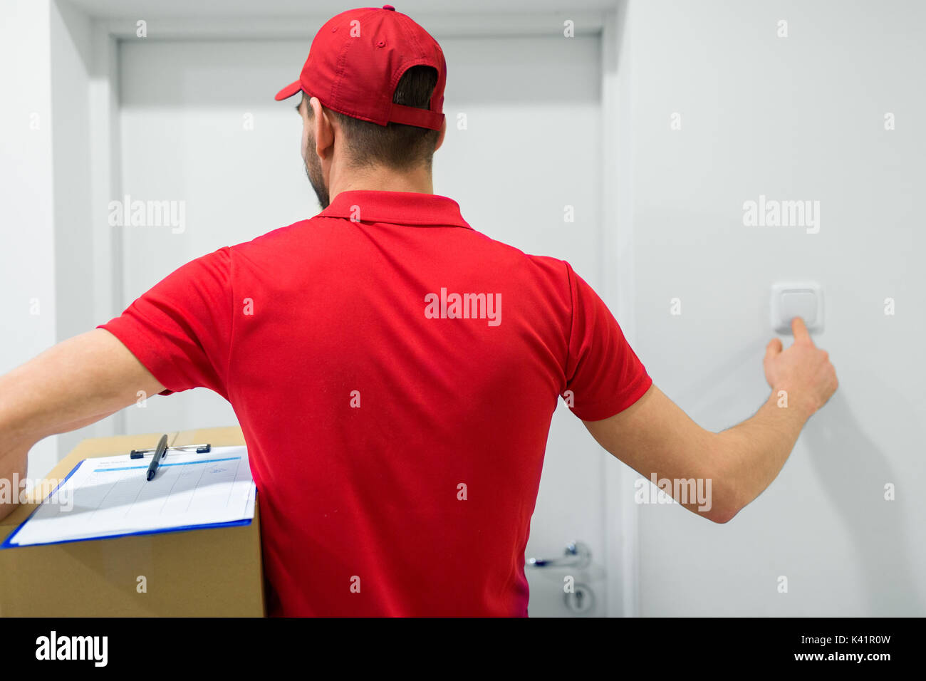 delivery man with parcel box ringing door bell Stock Photo