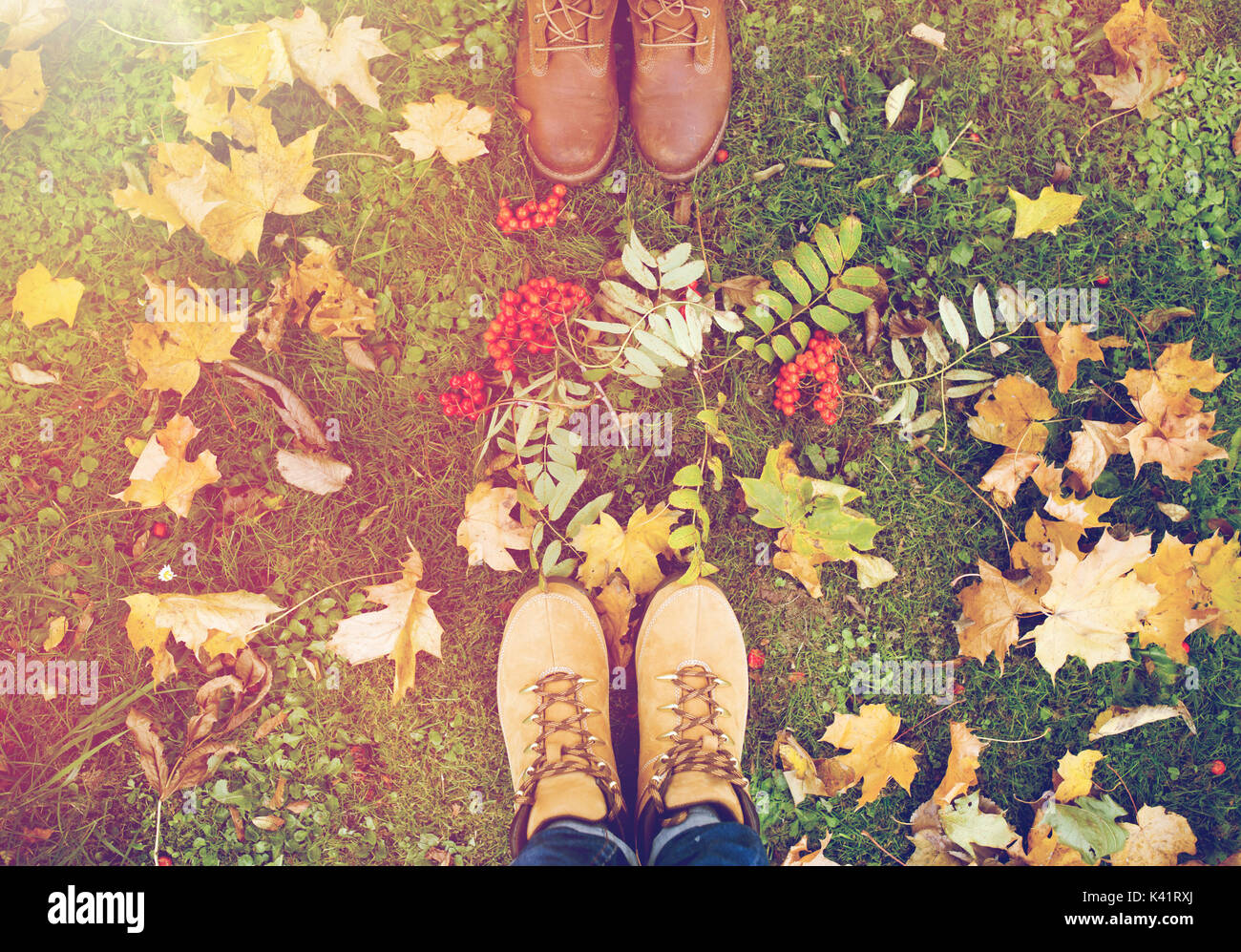 feet in boots with rowanberries and autumn leaves Stock Photo