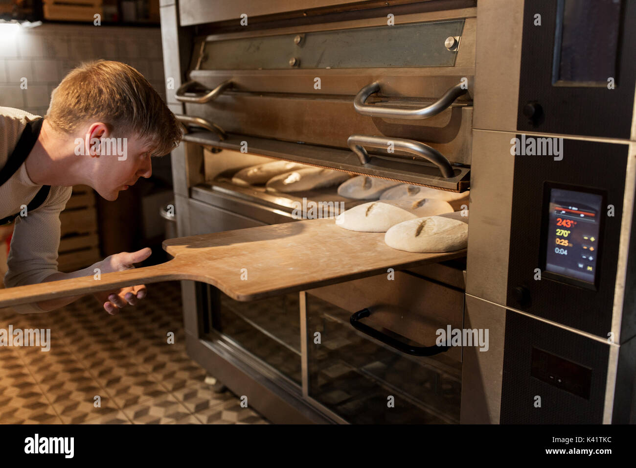 baker putting dough into bread oven at bakery Stock Photo Alamy