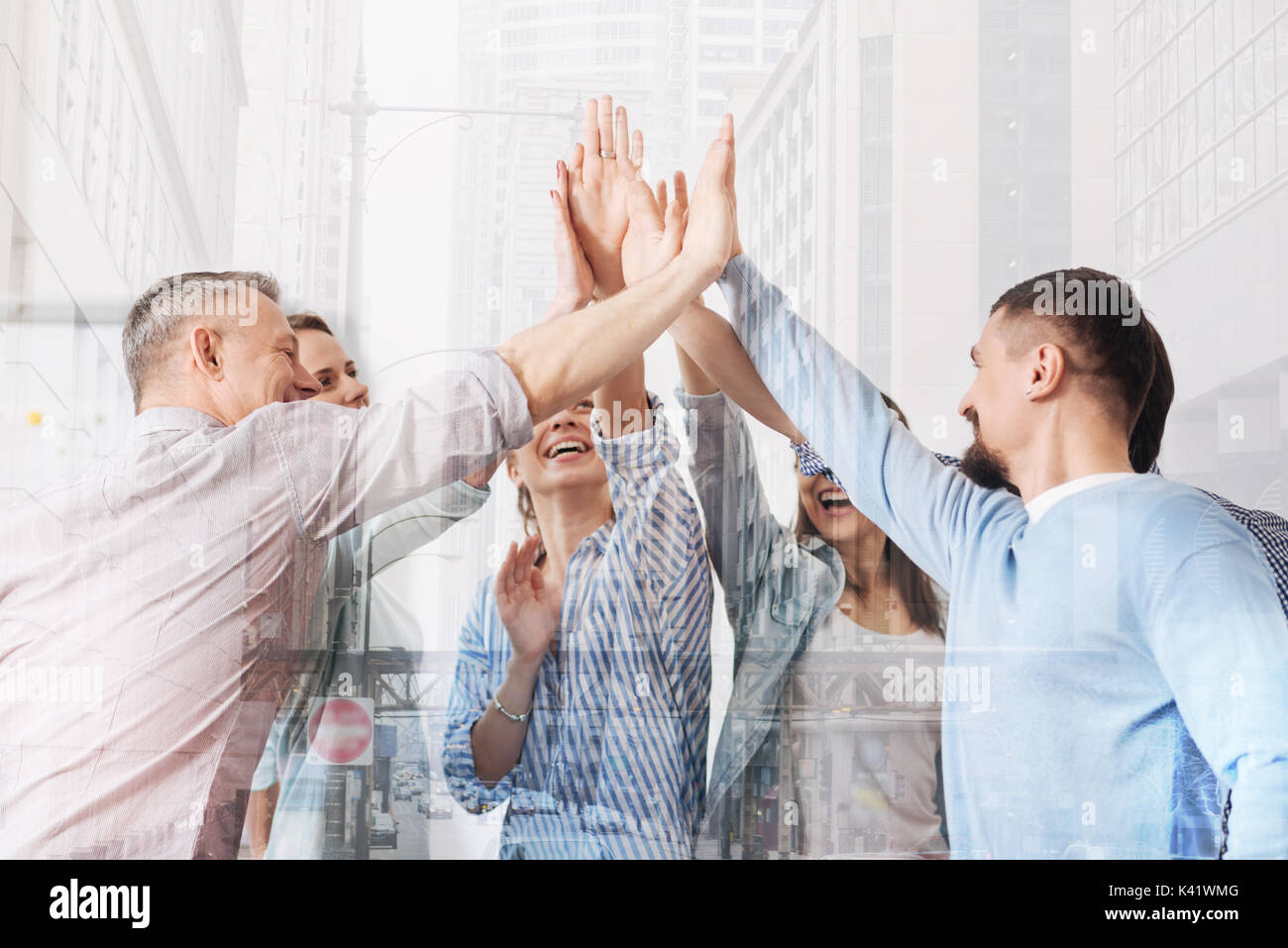Cheerful office workers giving high five each other Stock Photo