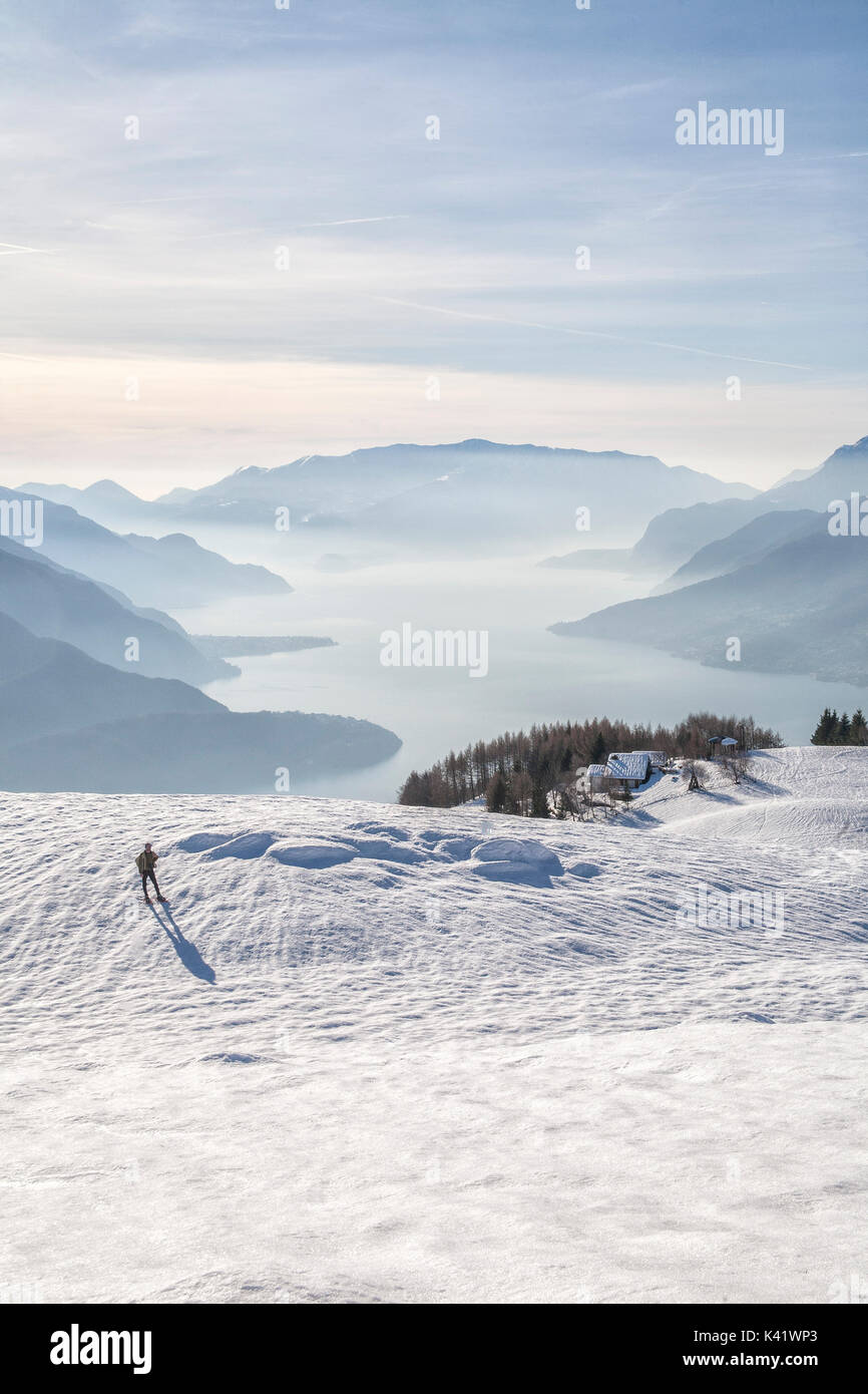 Hiker admires Lake Como on a cold winter morning Vercana mountains High Lario Lombardy Italy Europe Stock Photo