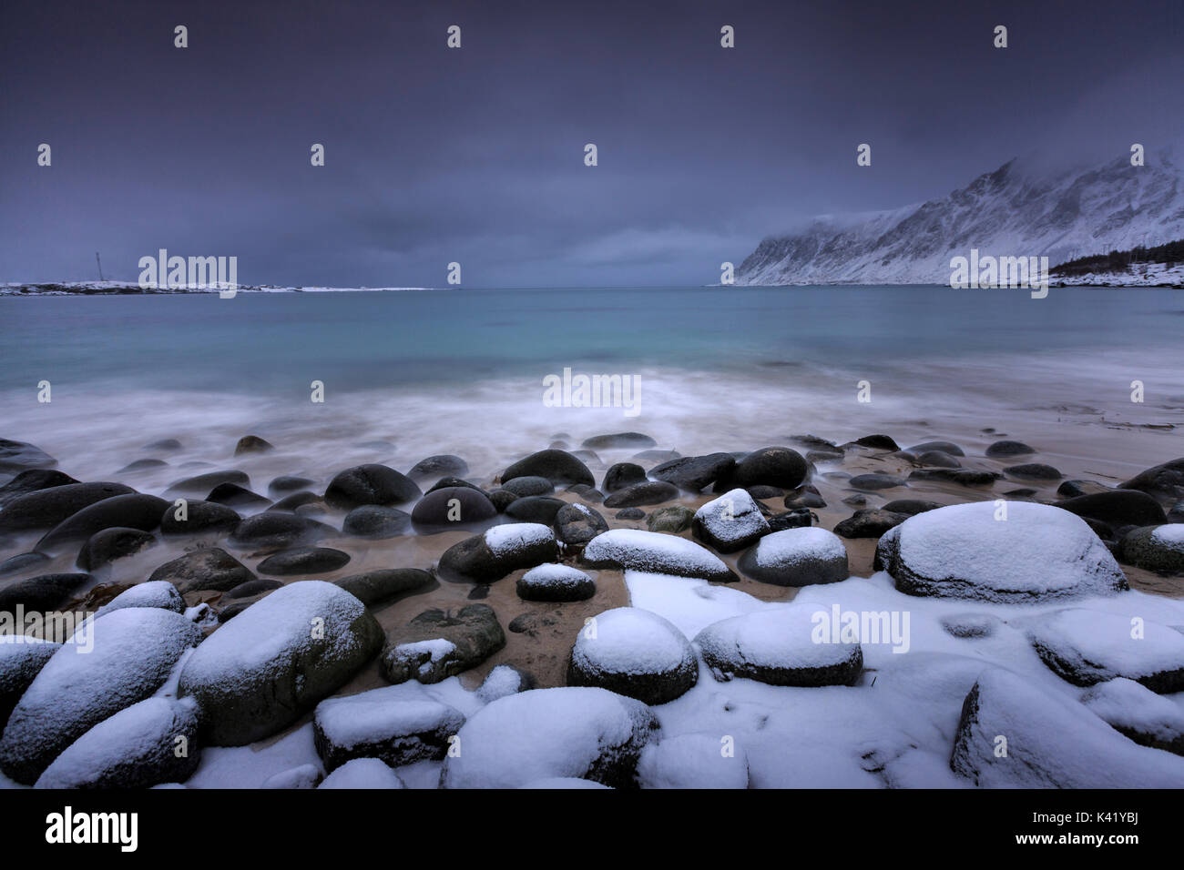 Snow covered rocks on the beach modeled by the wind surround the icy sea Pollen Vareid Flakstad Lofoten Islands Norway Europe Stock Photo