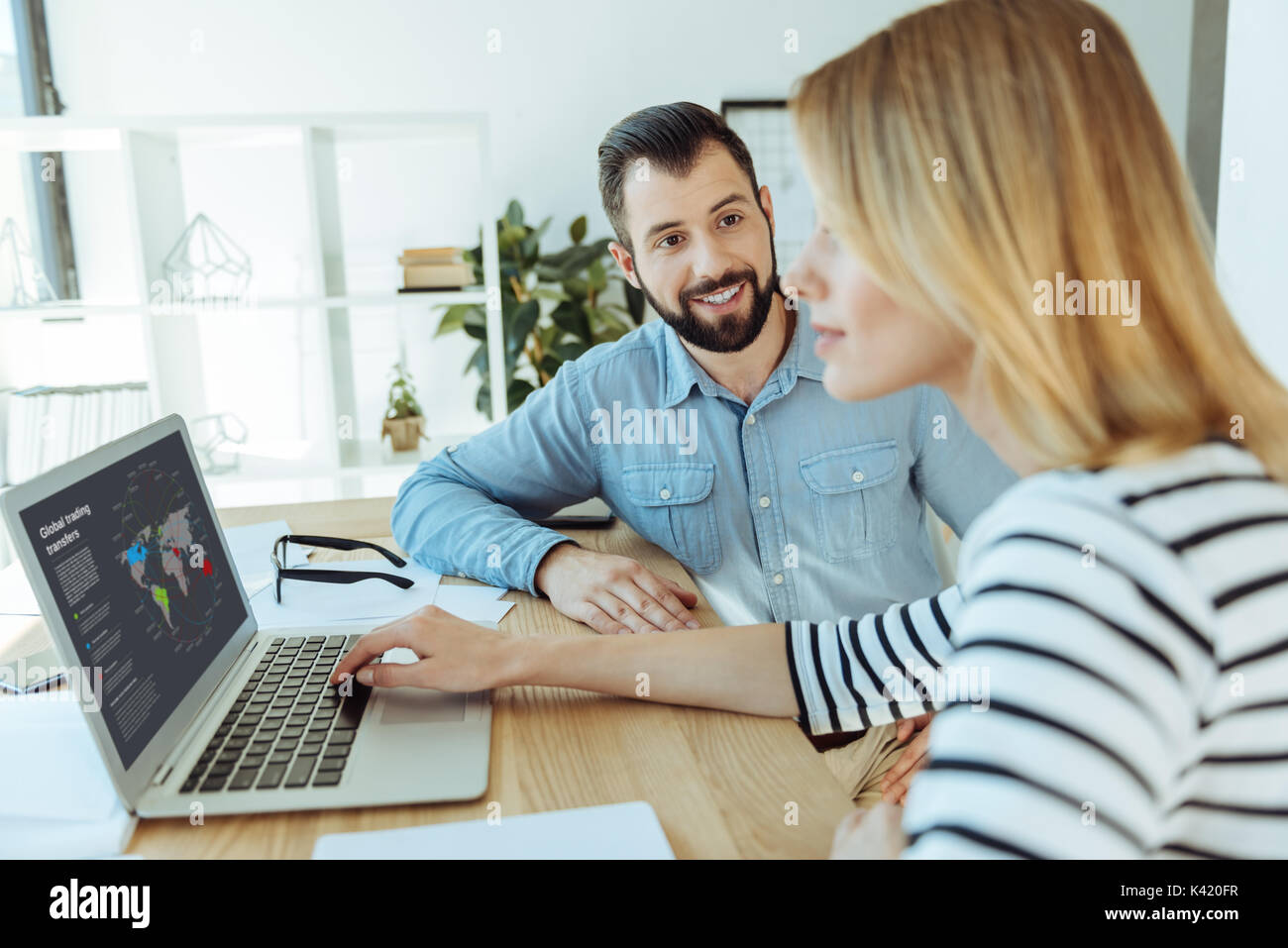 Smiling man watching colleague read infographics on laptop Stock Photo