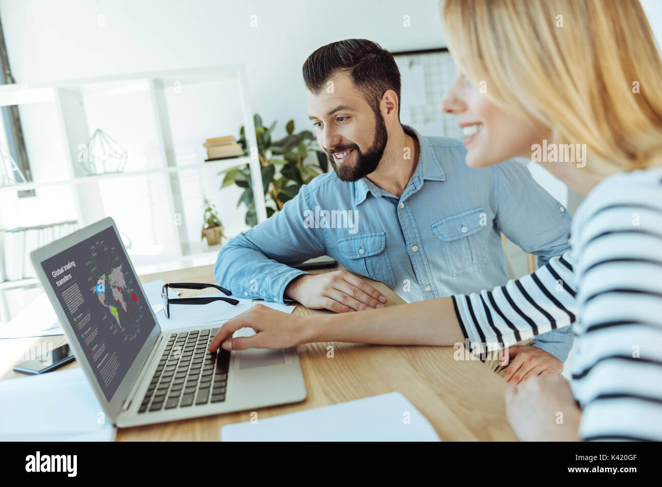 Cheerful colleagues watching a presentation on laptop together Stock Photo