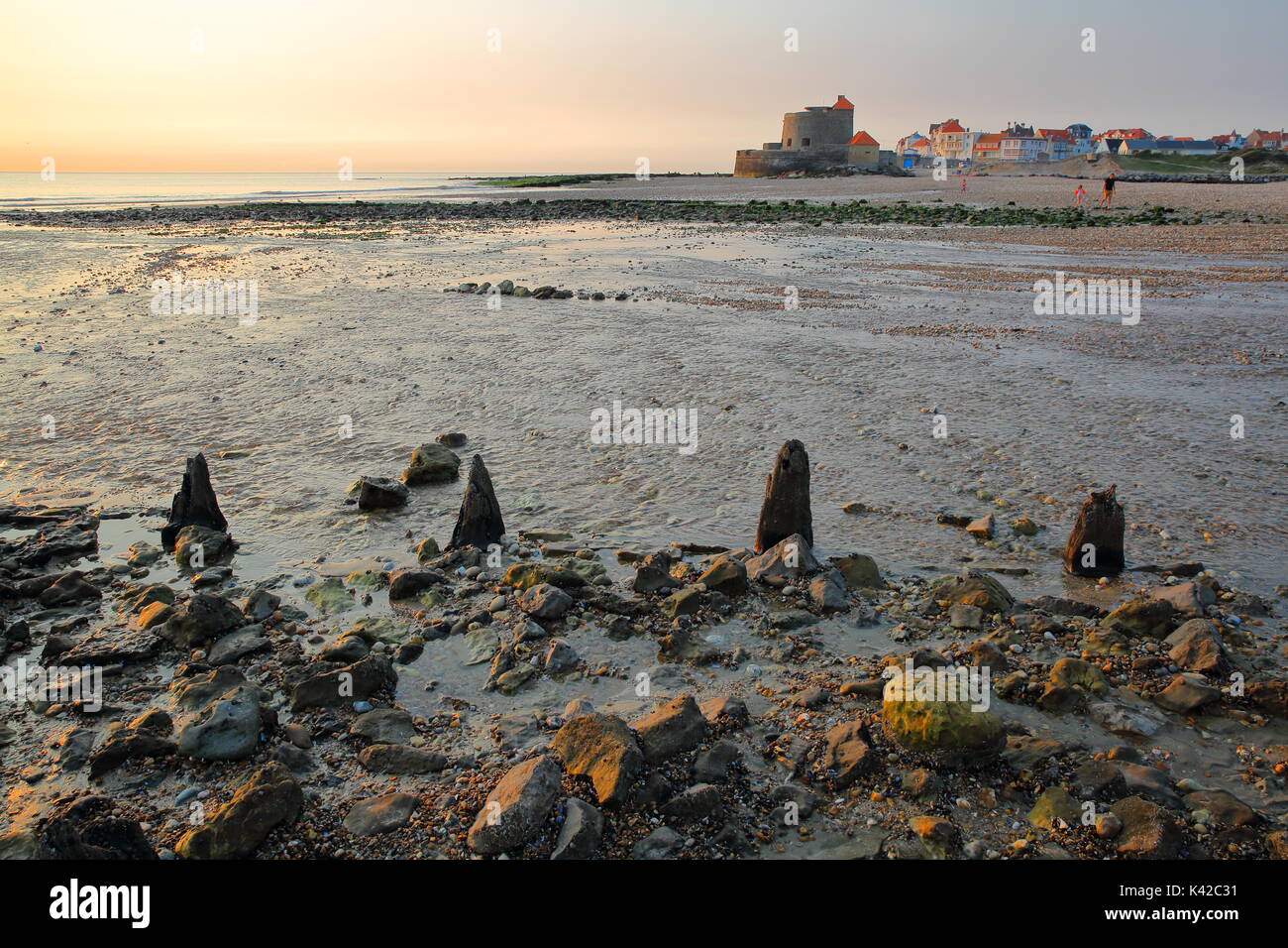 The beach of Ambleteuse at sunset with colorful stones in the foreground and the fort in the background, Cote d'Opale, Pas de Calais, Hauts de France Stock Photo