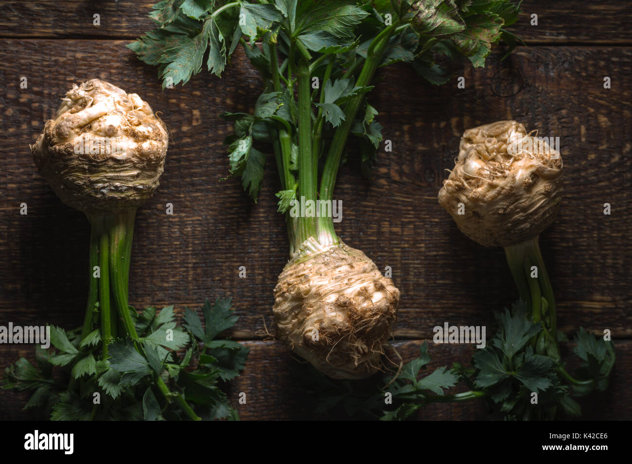 Celery roots with green leaves on brown boards horizontal Stock Photo