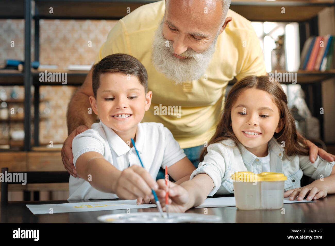 Grandfather watching adorable little siblings choose watercolors Stock Photo