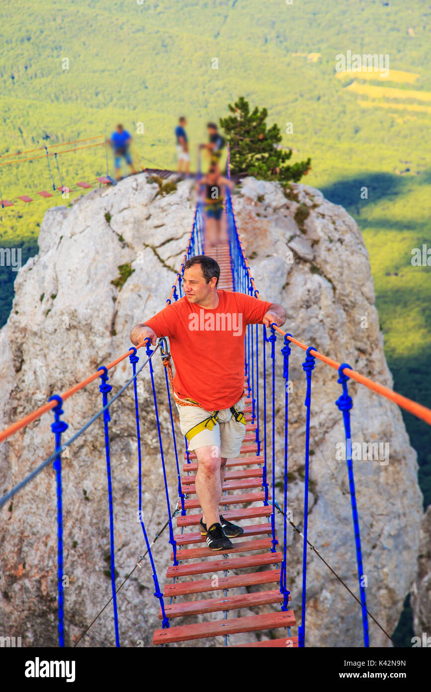 Man is walking along a suspension bridge over an abyss. Yalta, the Crimea. The concept of risk and danger. Stock Photo