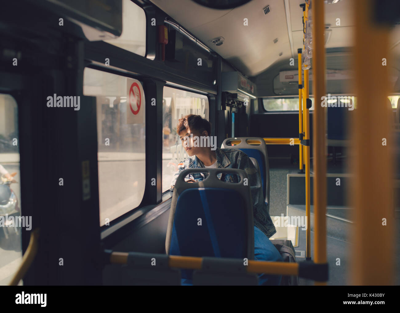 Asian man sitting dreaming on bus looking through window. Stock Photo