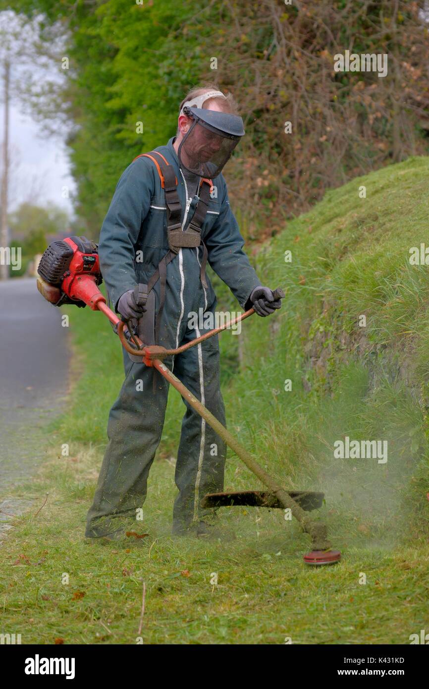 Man cutting grass verge with brushcutter Stock Photo