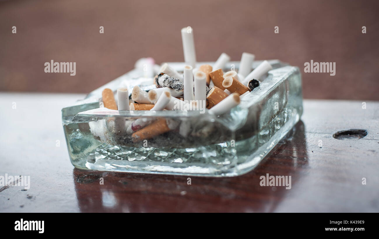 The dirty ashtray is full of cigarettes butt and ashes. Real life scene