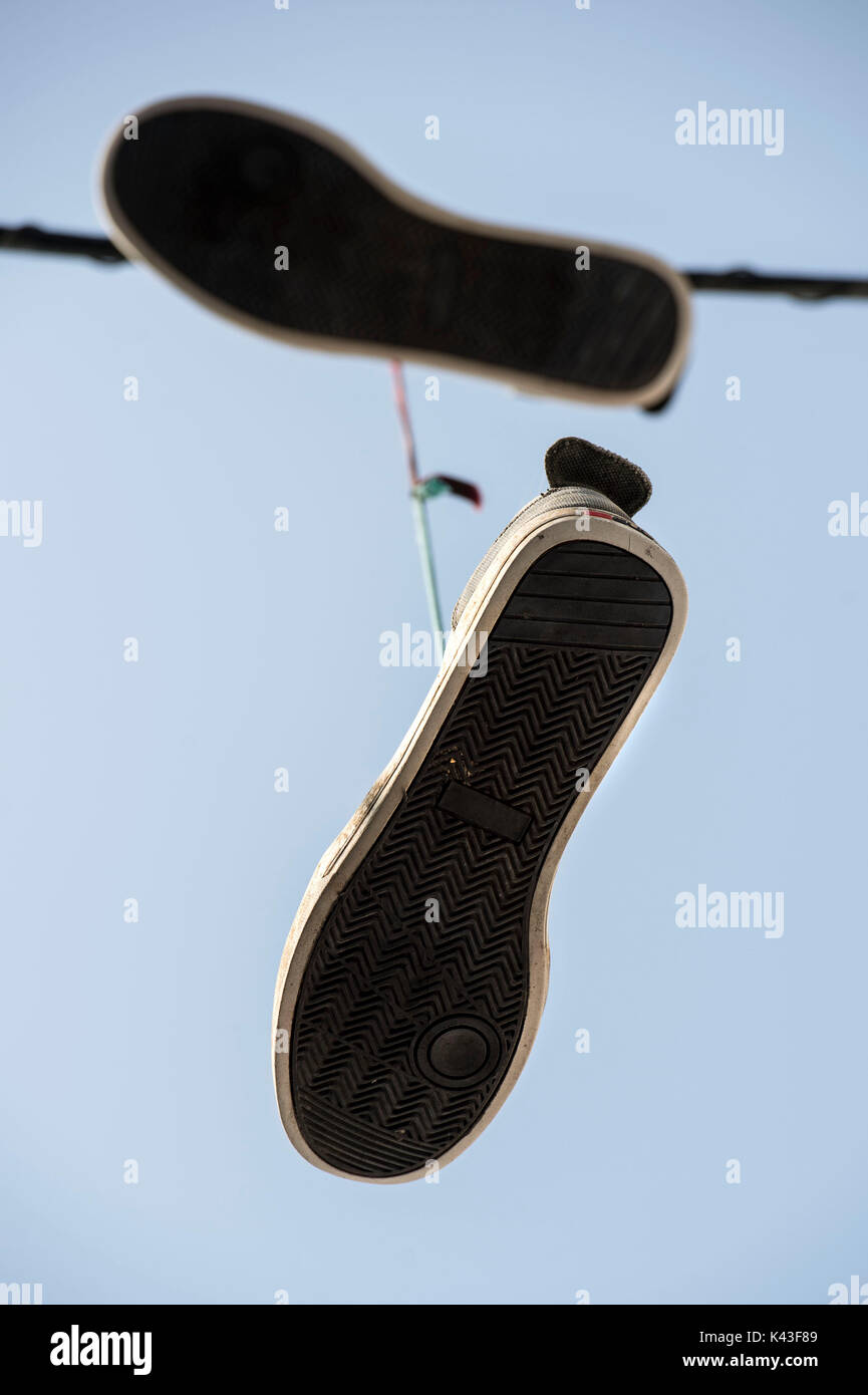 Canvas shoes hanging by the laces from a utility cable above