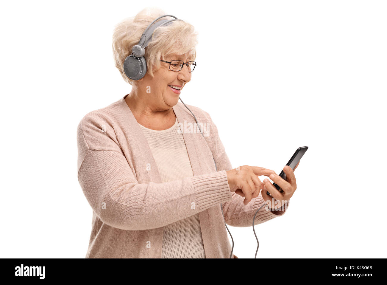 Elderly woman with headphones listening to music on a phone isolated on white background Stock Photo