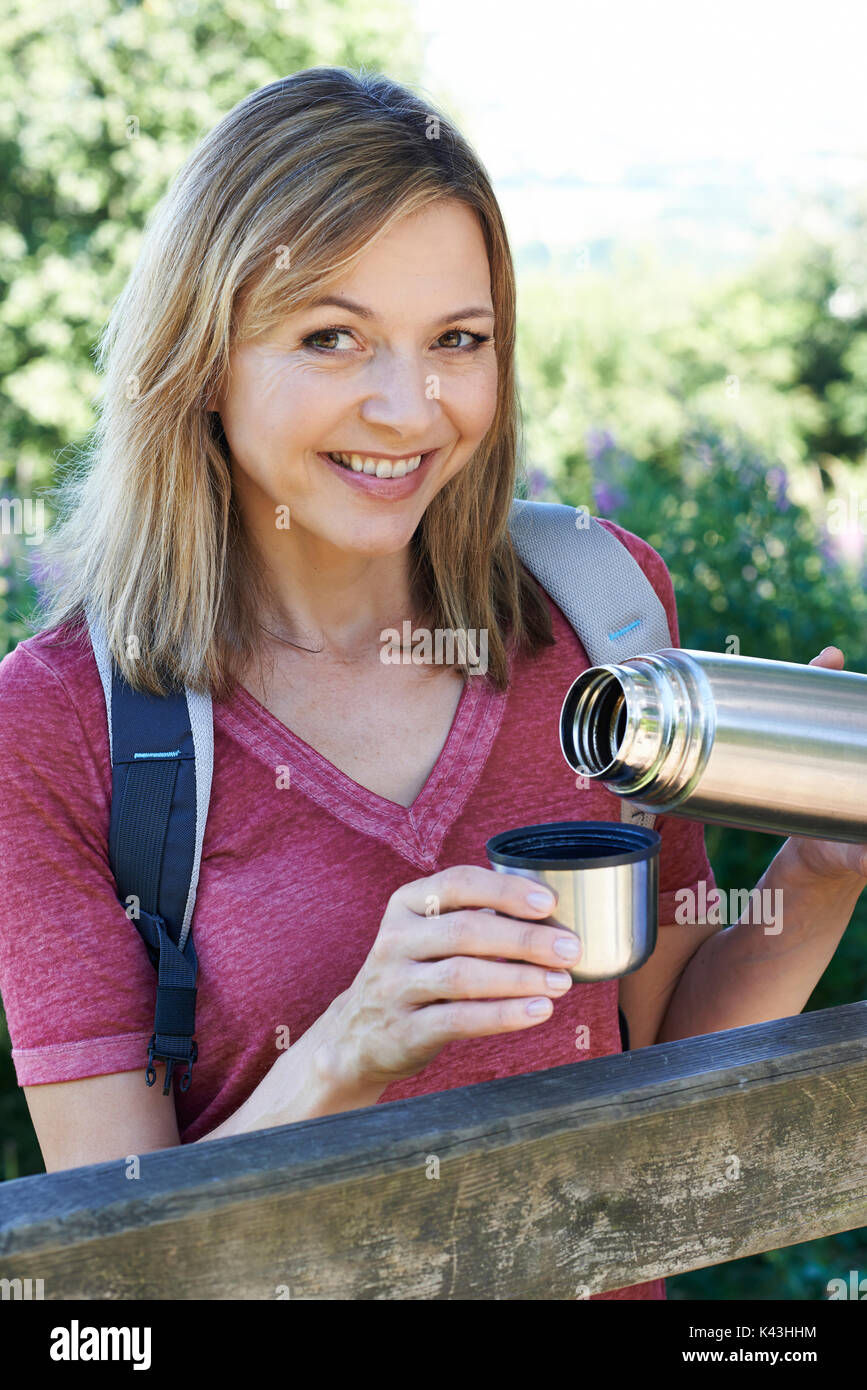 Mature Woman Pouring Hot Drink From Flask On Walk Stock Photo